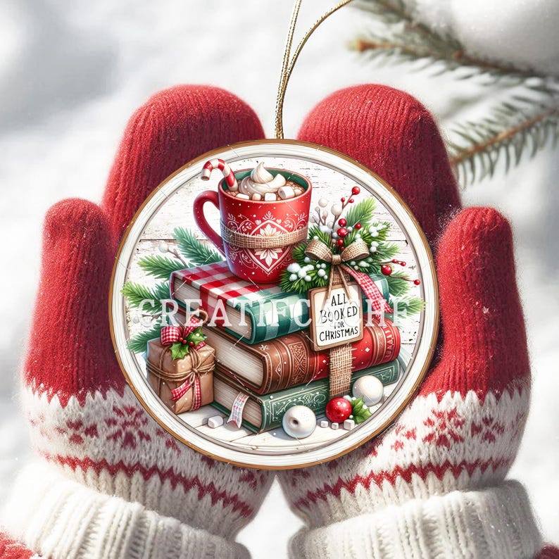May include: A circular Christmas decoration depicting books, a hot chocolate mug, and a wrapped present. The ornament reads "ALL BOOKED FOR CHRISTMAS" and is held by red mittens with a white snowflake design. The ornament is held by red mittens.