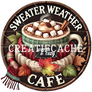 May include: A round wooden sign with the words "SWEATER WEATHER CAFE" in white. The sign features a mug of hot chocolate with marshmallows, a cinnamon stick, and fall leaves. The words "Warm & Cozy" are also included.