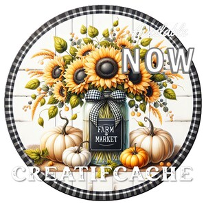 May include: A round wooden sign with a black and white checkered border. The center of the sign features a white background with a wood plank design. A mason jar filled with sunflowers and greenery sits in the center of the sign. Two white pumpkins and one orange pumpkin are placed in front of the jar. The sign also includes the text "Farm & Market" on a black chalkboard label attached to the jar and the text "Available Now" in white letters on a black background. The bottom of the sign reads "CreatIfCache".