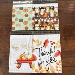 May include: Four fall-themed poly mailer bags. One bag features pumpkins on a green background. Another has mason jars and leaves on a wood background. The third bag has a wagon filled with pumpkins. The fourth bag says "Thankful for You".