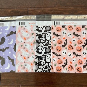 May include: Three different Halloween-themed mailing envelopes. The first envelope is purple with bats and stars. The second envelope is pink with ghosts and leaves. The third envelope is pink with pumpkins, bats, and skulls. All envelopes have the text "#SmileMail" and "10x13" printed on them.