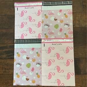May include: Four pink and white poly mailers with a flamingo and tropical print. The mailers have the text "#SmileMail by UpShip" printed on them.