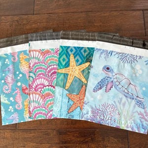 May include: A collection of colorful poly mailer shipping bags with ocean-themed designs. The bags feature seahorses, seashells, starfish, and a sea turtle. The color palette includes shades of blue, pink, orange, and teal.