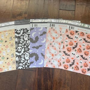 Könnte beinhalten: Fünf verschiedene Halloween-bedruckte Versandtaschen mit verschiedenen Mustern. Die Muster beinhalten Geister, Fledermäuse, Kürbisse, Schädel und die Wörter "boo" und "Smile Mail Ya'll".