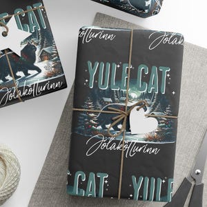 May include: Wrapped gifts with a black background featuring a Yule Cat design. The gifts are tied with twine and adorned with white star and heart-shaped tags. A ball of twine, scissors, and additional tags are also present.