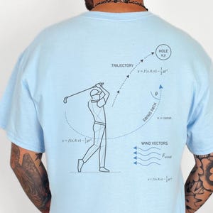 May include: Light blue t-shirts with golf-themed graphics. One shirt features the name "david" with a golfer illustration. The other shirt displays a golf swing diagram with trajectory and wind vector details.