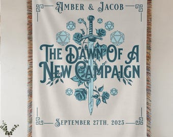 Può includere: Arazzo tessuto color crema con bordo decorativo e frange. L'arazzo presenta il testo "AMBER & JACOB" e "THE DAWN OF A NEW CAMPAIGN" in verde acqua. Sono raffigurati anche una spada, rose e forme geometriche. È inclusa la data "SEPTEMBER 27TH, 2025".