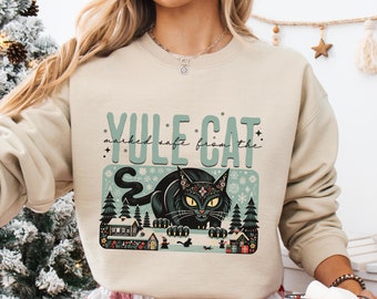 May include: A beige sweatshirt with a black cat illustration and the text "YULE CAT marked safe from the..." printed on the front.
