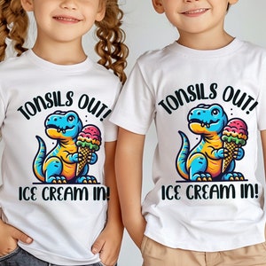 Pode incluir: Duas camisetas brancas com um dinossauro de desenho animado segurando um cone de sorvete. O texto nas camisetas diz "Tonsils Out! Ice Cream In!"