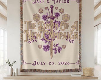 Può includere: Coperta tessuta color crema con un design decorativo. Il design include una spada, rose e forme geometriche, con il testo "The Dawn Of A New Campaign", "Jake & Taylor" e "July 25, 2026" in viola.