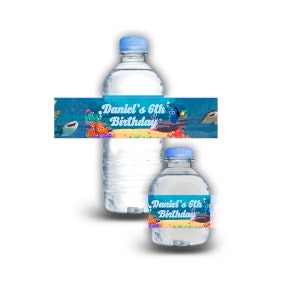 Peut inclure: Deux bouteilles d'eau en plastique transparent avec des étiquettes bleues. Les étiquettes présentent une image de dessin animé de Dory et Nemo du film Le Monde de Nemo. Les étiquettes comprennent également le texte "Daniel's 6th Birthday".