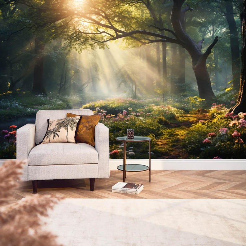 May include: A cozy living room scene featuring a light gray armchair with two decorative pillows. A small, round side table holds a glass and a book. The backdrop is a vibrant forest mural with sunlight streaming through the trees.