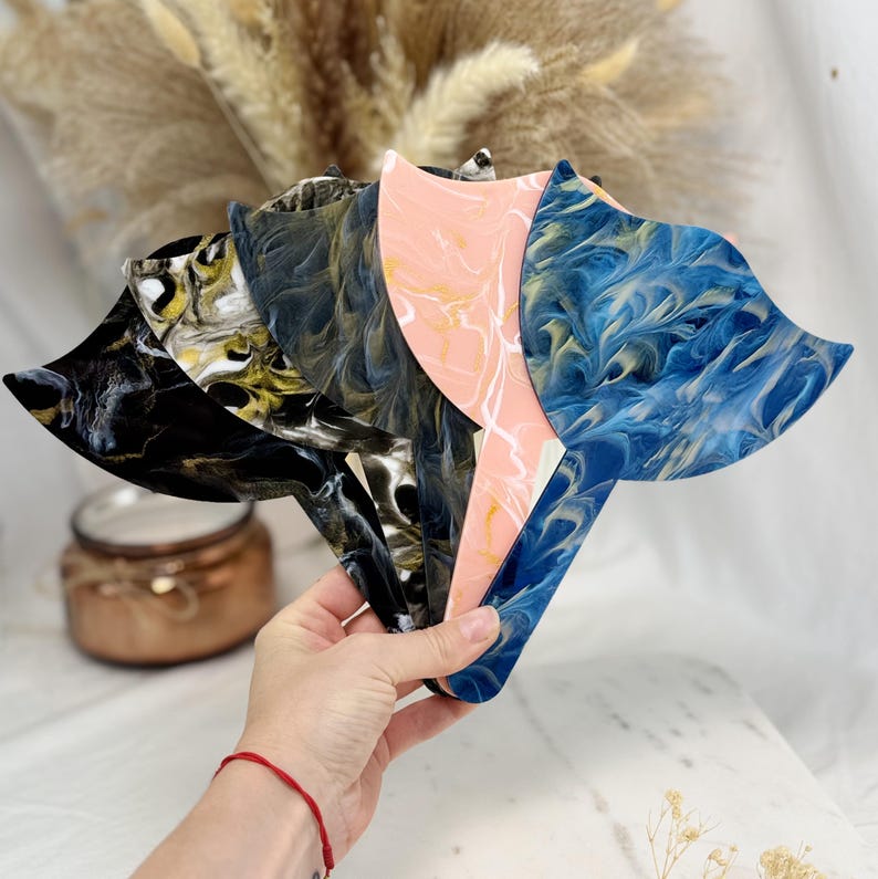 Puede incluir: Una colecci&oacute;n de cinco abanicos decorativos con patrones &uacute;nicos y arremolinados. Los abanicos muestran una variedad de colores, incluyendo negro, dorado, azul marino, rosa y azul. Cada abanico tiene una forma y dise&ntilde;o distintivos.