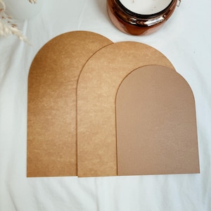 May include: Three brown arch-shaped cardboard pieces, arranged in descending size order, with the largest piece at the back and the smallest piece at the front.
