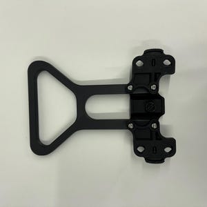 May include: Black metal camera cage with a triangular handle and adjustable mounting points.