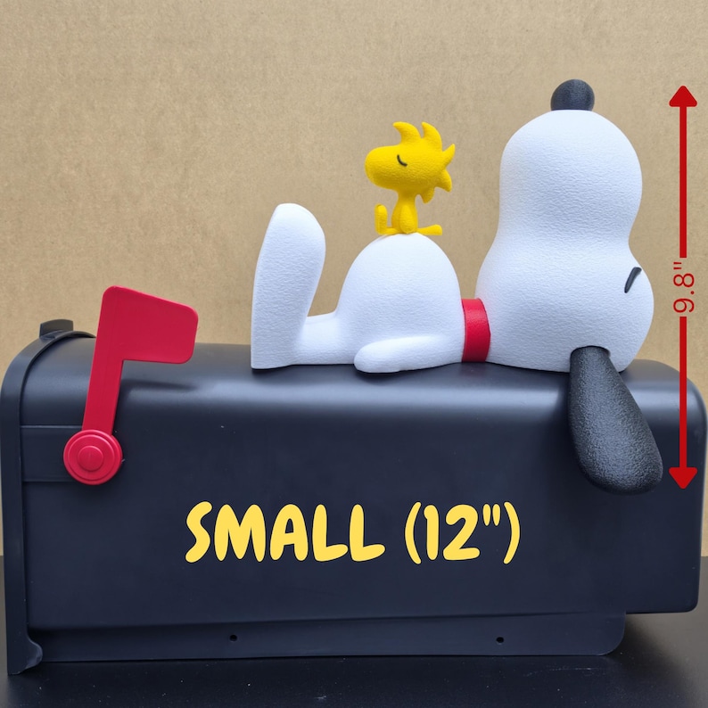 May include: A black mailbox featuring a white dog figure with a black ear and red collar, topped with a yellow bird figure. The mailbox has a red flag and the yellow text SMALL (12"). A red arrow indicates a height of 9.8 inches.