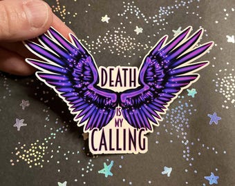May include: A sticker with a pair of purple and blue angel wings with the text "Death is my calling" in white.