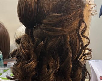 May include: A brown wig with long, curly hair styled in two buns on top of the head. The wig is on a mannequin head.