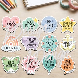 Puede incluir: Una colección de pegatinas coloridas troqueladas con citas inspiradoras y temas religiosos. Los diseños incluyen un arcoíris, una mariposa, una oveja y varias formas con frases como "Confía en Dios" y "Ámense los unos a los otros".