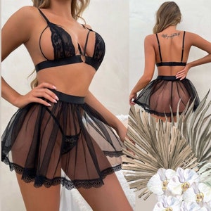 The skirt has a thick, opaque waistband that creates a cinched effect, and the hem is trimmed with a matching floral lace pattern, echoing the lace design of the bralette.