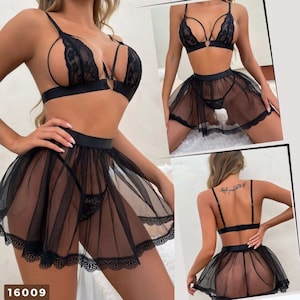 The image showcases a lingerie set with several detailed views. The set includes a black bralette top with lace cups and straps that form a harness design over the chest, accentuated with a center ring connecting the cups and straps.