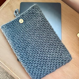 May include: A gray crocheted tablet sleeve with a wooden button closure.
