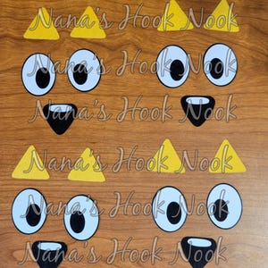 May include: Four sets of felt animal face parts, including yellow triangle ears, black noses, and white eyes with black pupils. The text "Nana's Hook Nook" is repeated four times on the brown wood background.