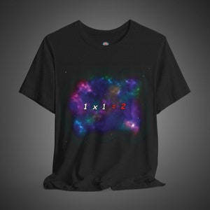 Puede incluir: Camiseta negra con estampado de nebulosa colorida y el texto "1 x 1 = 2" en blanco y rojo.