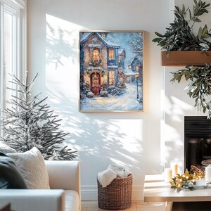 May include: A framed painting of a snow-covered village scene with a house decorated for Christmas. The house has a red door and a wreath with a red bow. The windows are lit up and there is snow falling in the background.