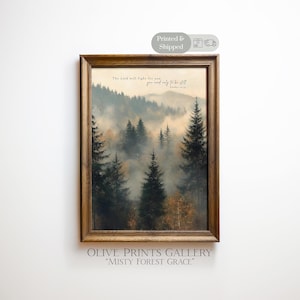 May include: A framed print featuring a misty forest scene with tall evergreen trees and a mountain range in the background. The artwork has a warm color palette and includes the text "The Lord will fight for you, you need only to be still."