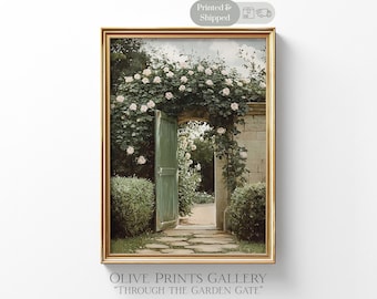 May include: A framed print of a garden scene with a green door and archway covered in white roses. The print has a gold frame and the text "OLIVE PRINTS GALLERY" and "THROUGH THE GARDEN GATE" at the bottom. The image also has a "Printed & Shipped" sticker.