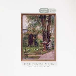 May include: A framed print of a garden scene with a table and chair. The artwork features a wooden frame and depicts a lush garden with a table, chair, and a small building covered in greenery. The text "OLIVE PRINTS GALLERY" and "QUIET GARDEN SCENE" are visible.