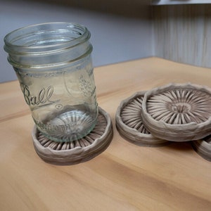 May include: Four brown mushroom-shaped coasters with a textured surface. A clear glass jar is sitting on one of the coasters.
