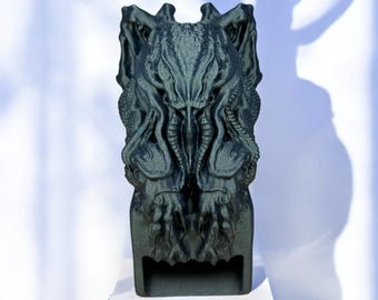 Puede incluir: Una escultura en 3D impresa de color verde oscuro que representa a una criatura con una cabeza grande y múltiples tentáculos. La escultura es detallada y tiene una superficie texturizada.