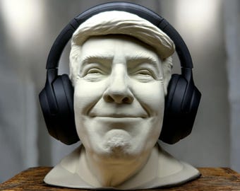 May include: A white plaster bust of a person wearing black over-ear headphones. The person is smiling.