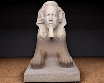 Puede incluir: Una detallada escultura de color blanquecino de una esfinge. La esfinge tiene una cabeza humana con una expresión serena, un tocado tradicional y una barba prominente. El cuerpo es el de un león, con las patas extendidas. La escultura está sobre un fondo oscuro.