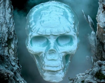 May include: A blue and white 3D printed skull with a smoky background. The skull is surrounded by tree bark.