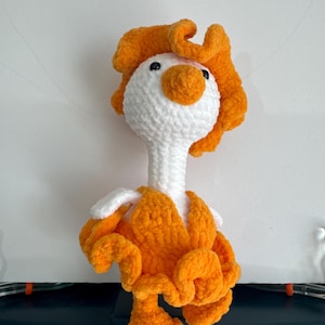 May include: A crocheted stuffed goose toy with a white body and orange head, wings, and legs.