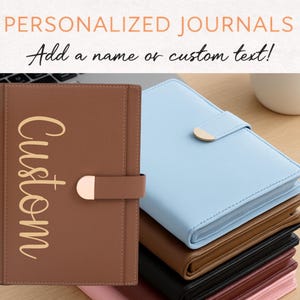 May include: A stack of personalized journals in various colors, including brown, blue, and black. The brown journal has the word "Custom" in gold script. The journals have a clasp closure and are displayed on a light-colored surface. The text at the top says "PERSONALIZED JOURNALS" and "Add a name or custom text!"