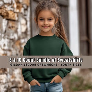 May include: A young person wearing a dark green crewneck sweatshirt and blue jeans. The sweatshirt has a round neckline and long sleeves. Text on the image reads: "5 & 10 Count Bundle of Sweatshirts" and "GILDAN 18000B CREWNECKS - YOUTH SIZES."