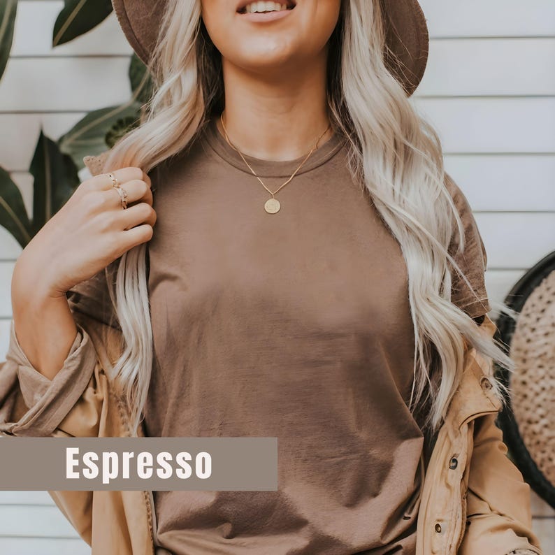 May include: Espresso-colored t-shirt with a round neckline. The shirt is paired with a tan jacket and a gold necklace with a circular pendant. The word "Espresso" is displayed in a rectangular box at the bottom of the image.