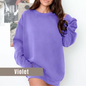 May include: A violet-colored sweatshirt with a crew neck and long sleeves. The word "Violet" is displayed in a rectangular box at the bottom of the image. The sweatshirt is made of a soft, comfortable material.