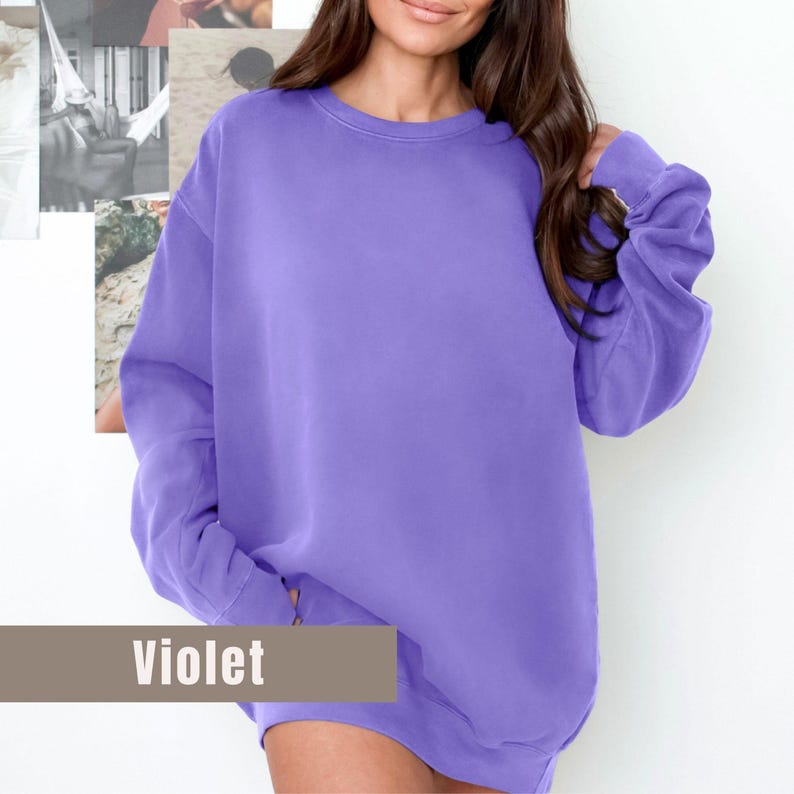 May include: A violet-colored sweatshirt with a crew neck and long sleeves. The word "Violet" is displayed in a rectangular box at the bottom of the image. The sweatshirt is made of a soft, comfortable material.