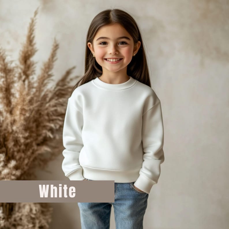 May include: A young person wearing a white sweatshirt and blue jeans. The sweatshirt has a crew neck and long sleeves. The word "White" is displayed in a banner at the bottom of the image.