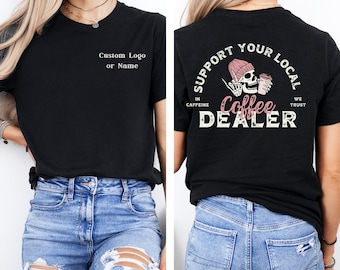 May include: Black t-shirt with a skull holding a coffee cup and the text "Support Your Local Coffee Dealer" on the back. The front of the shirt has the text "Custom Logo or Name".
