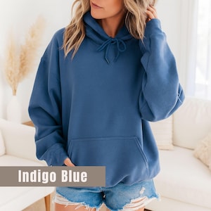 Op de afbeelding: Indigo blauwe hoodie met een trekkoord en een kangoeroezak aan de voorkant. De sweatshirt is effen van kleur en gemaakt van een zacht materiaal. De tekst "Indigo Blue" wordt onderaan de afbeelding weergegeven.