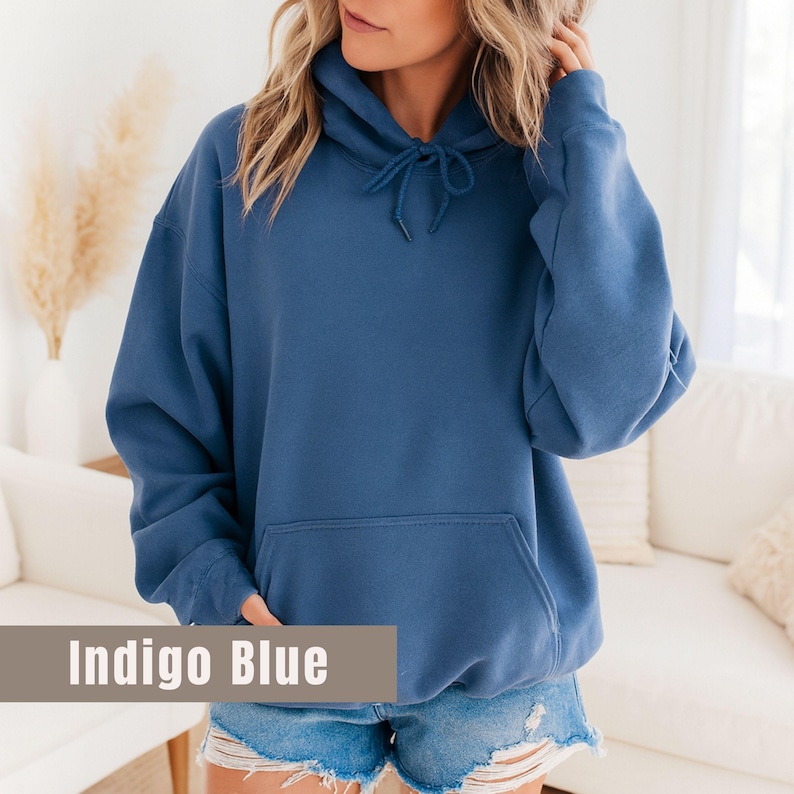 Op de afbeelding: Indigo blauwe hoodie met een trekkoord en een kangoeroezak aan de voorkant. De sweatshirt is effen van kleur en gemaakt van een zacht materiaal. De tekst "Indigo Blue" wordt onderaan de afbeelding weergegeven.
