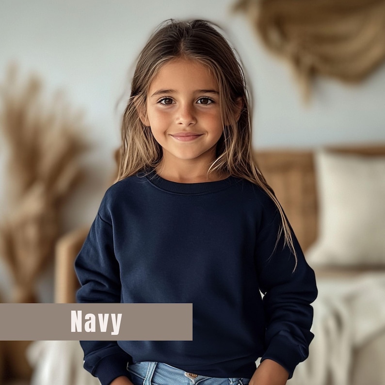 May include: A navy blue sweatshirt with the word "Navy" in a tan rectangle. The sweatshirt is long-sleeved and appears to be made of a soft material. The sweatshirt is being worn by a young person.