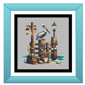 May include: A framed cross-stitch design featuring a pelican perched on a wooden pier with nautical elements. The artwork includes a pelican, pier posts, lanterns, beach balls, and the text "Pelican Perch" in teal.
