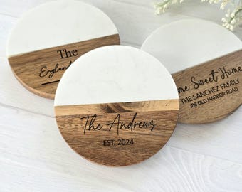 May include: Set of three round coasters with a white marble top and a brown wood base. The coasters are personalized with the text "The England", "The Andrews EST. 2024", and "Home Sweet Home THE SANCHEZ FAMILY 108 OLD HARBOR ROAD".